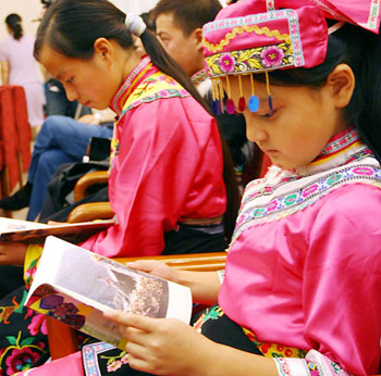  Two Qiang girl student from the quake-hit Sichuan Province reads a text book about the Qiang culture during a book donation ceremony held in Beijing on September 10, 2008.