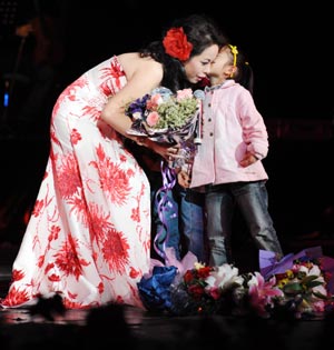 Singer Bai Lu receives floral tribute from a kid while rendering the song of the late Taiwanese popular singer Terasa Teng, during the premiere of a grand tour vocal concert in honour of Terasa Teng at the grand theatre of Guiyang, southwest China's Guizhou Province, Oct. 25, 2008. 