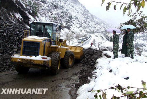 Highway maintenance workers use a bulldozer to clear a section of the Sichuan-Tibet road yesterday. 