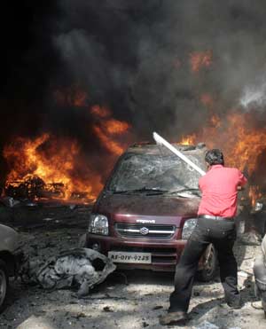 A man breaks the windscreen of a car to look for people possibly trapped inside the car after a bomb blast in Guwahati, the main city of India&apos;s troubled northeastern Assam state, Oct. 30, 2008. [Xinhua]