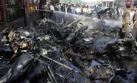 Onlookers and police stand near destroyed vehicles and dead bodies lying at one of the sites of bomb blasts in Guwahati, the main city of India&apos;s troubled northeastern Assam state, Oct. 30, 2008. [Xinhua/Reuter]