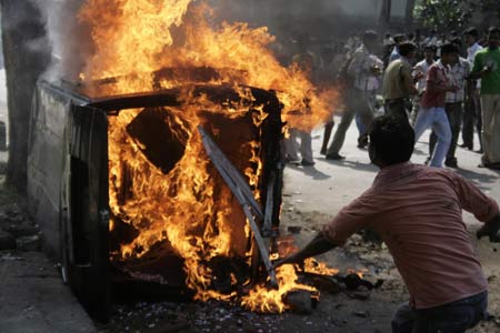 A man tries to extinguish a burning vehicle at one of the sites of bomb blasts in Guwahati, the main city of India&apos;s troubled northeastern Assam state, Oct. 30, 2008. [Xinhua/Reuters]