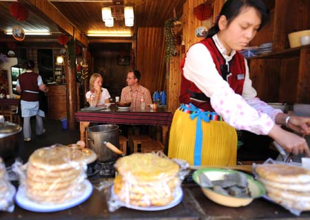 This photo dated on Oct. 24, 2008 shows tourists enjoy local food in ancient Lijiang city, southwest China's Yunnan Province. [Xinhua]