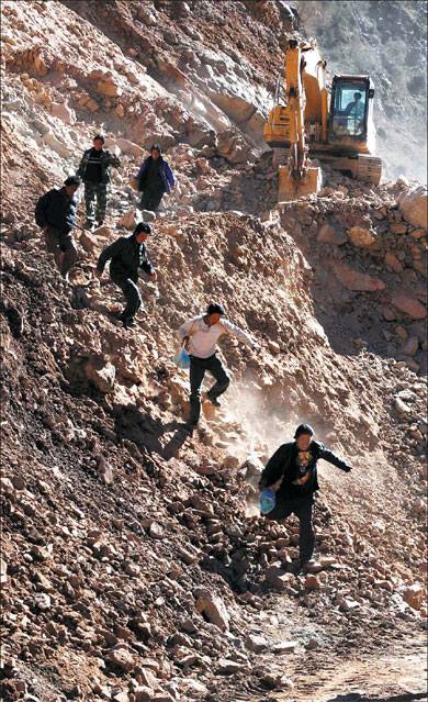 Rain devastates southwest People run to avoid being caught in a mudslide as workers try to rebuild a road blocked by landslides in Deqin, Yunnan province, yesterday. Heavy downpours, accompanied by squalls, have lashed Southwest China over the weekend, leaving 20 people dead and 42 missing in Yunnan. Floods triggered by torrential rain since Friday have claimed one life in the Guangxi Zhuang autonomous region, too, where nine persons are missing and 70,000 have been moved to safer places. [Xinhua]