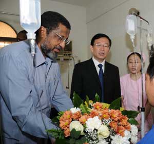 Sudanese Minister of Energy and Mining Al-Zobeir Ahmed Hassan (1st L) presents flowers to a surviving Chinese worker as Chinese Ambassador to Sudan Li Chengwen (2nd L) stands aside at a hospital in Khartoum Nov. 2, 2008. 