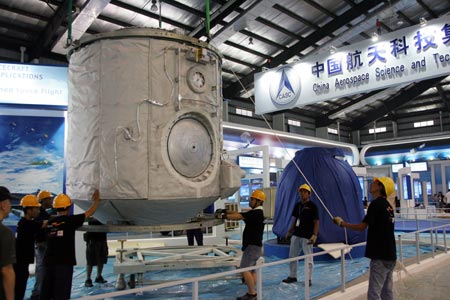 Workers try to put the orbital module of the Shenzhou VII spacecraft in its exhibition stand for the upcoming 7th China International Aviation and Aerospace Exhibition in this photo taken in Zhuhai, Guangdong Province, October 30, 2008. A series of new missiles, weapons and China's homegrown CH-3 unmanned fighter plane will make their public debut at the exhibition, which is scheduled to open from November 4 to 9, 2008. [Xinhua] 