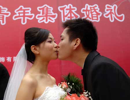 Newly-weds of migrant workers kiss each other during a group wedding in southwest China&apos;s Chongqing Municipality, Nov. 2, 2008. Thirty couple of migrant workers held group wedding here on Sunday. 