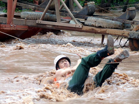 A firefighter climbs across a wire rope amid floods to evacuate stranded residents in Lufeng county, southwest China's Yunnan province November 2, 2008. Heavy rainfall hit the area last weekend and caused torrents of mud and rock, which have affected nearly 1 million people in 13 counties of the Chuxiong Yi autonomous prefecture in the province, killing at least 35. [CFP]