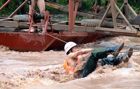 A firefighter crosses a river using a rope to rescue villagers in Lufeng county, November 3, 2008. [China Daily] 