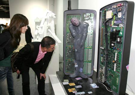 Visitors view the sculpture titled 'The Number You Dialed is Busy Now...' exhibited on the first China Great Mobile Exhibition of Sculptures opened in Wenzhou city of east China's Zhejiang Province, Nov. 5, 2008. [Xinhua] 