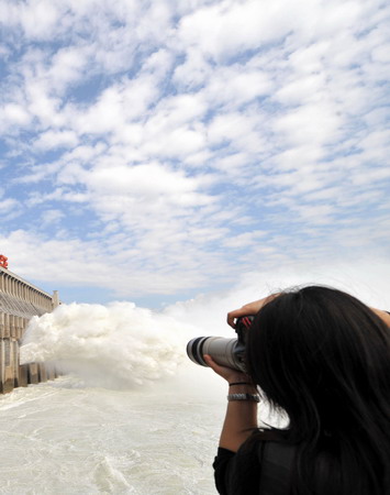 A journalist takes a photo of the Three Gorges Dam which is located in Yichang of central China's Hubei province on November 7, 2008. The dam starts to discharge water to face the infrequent winter flood as a result of continual rainfall in the upriver regions of the Yangtze River.[Xinhua] 