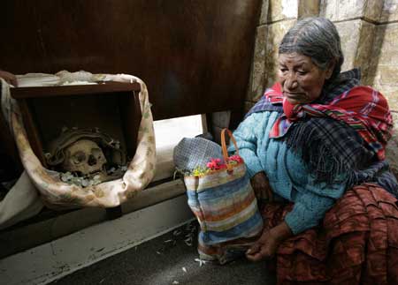 A Bolivian indigenous woman sits near a skull during a ceremony on the Day of Skulls in a church at the General Cemetery of La Paz November 8, 2008. Bolivians who keep close relatives&apos; skulls at home as a macabre talisman flock to the cemetery chapel once a year to have the craniums blessed and to bring themselves good luck in the future.