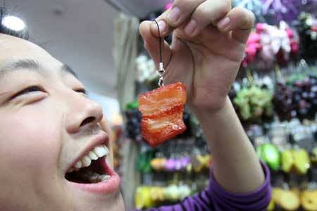 A teenager pretends to eat a meat-shaped accessory at the Tianyi Market in Beijing, capital of China, Nov. 8, 2008. Accessories made into the shape of food are popular among youngsters in Beijing.