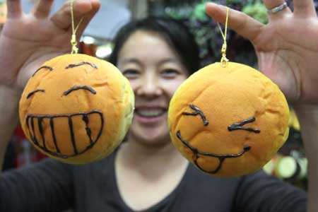 A girl shows two bread-shaped accessories at the Tianyi Market in Beijing, capital of China, Nov. 8, 2008. Accessories made into the shape of food are popular among youngsters in Beijing. 