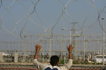 A worker stands behind wires in Gaza power plant, Gaza Strip, on Nov. 10, 2008. Gaza power plant, the main electricity supplier for the center and the south of the strip, was forced to shut down on Monday due to the Israeli blockade of fuel deliveries, leaving 800,000 people into blackout. (Xinhua Photo)