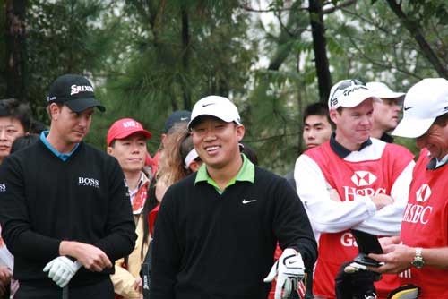 Anthony Kim's grin conceals a cunning plot he has hatched: 'I'm going to break my driver and get disqualified. That way I'll get out of this wet and cold.' Henrik Stenson already has his suspicions... [David Ferguson/China.org.cn]