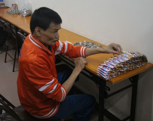 A-Gang, a 38-year-old mentally challenged man makes hair accessories at a training centre for people with intellectual disabilities at the Fengyuan Street residential area in Guangzhou on Monday, November 10th, 2008. 