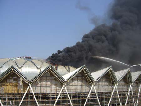 Firefighters try to extinguish fire at a stadium under construction in Jinan, capital of east China's Shandong Province, on Nov. 11, 2008. The indoor stadium under construction which is part of the Olympic Sports Center in the eastern suburbs of Jinan caught fire at around 11:30 a.m. Tuesday. The same stadium, built for the 11th National Games of China in 2009, once caught fire on July 27 due to sparks sprinkled out during the welding process. [Xinhua]