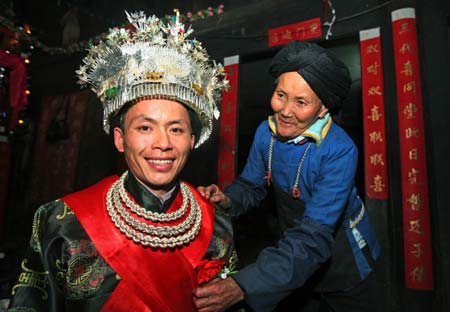 Bridegroom Li Youqing (L) dresses up before his ethical wedding with bride Zhao Minlian in Tonglian Township of Yao ethnic group in Rongshui County, southwest China's Guangxi Zhuang Autonomous Region, Nov. 9, 2008. 