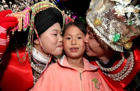 Bride Zhao Minlian (L) and bridegroom Li Youqing kiss their daughter on their ethical wedding in Tonglian Township of Yao ethnic group in Rongshui County, southwest China's Guangxi Zhuang Autonomous Region, Nov. 9, 2008. 