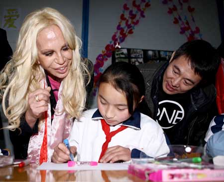 Italian designer Donatella Versace (L) and Chinese actor Jet Li watch a girl drawing at the Versace-One Foundation children center at Sanjiang, Wenchuan county, southwest China's Sichuan Province, Nov. 11, 2008. 
