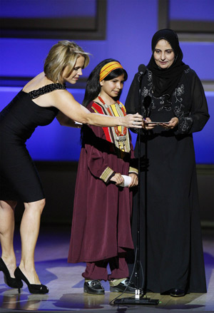 Television personality Katie Couric helps adjust a microphone for Yemeni former child bride Nujood Ali (C) and civil rights lawyer Shada Nasser (R) as they accept a Glamour Woman of the Year award at a ceremony in New York Nov. 10, 2008. 