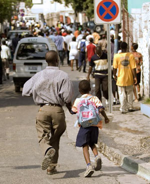 A father runs with his child after a school collapsed in Port-au-Prince November 12, 2008. 