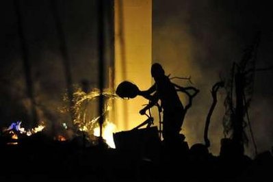 A man tries to put out a fire at a home in Santa Barbara, California November 14, 2008. A huge wildfire fanned by strong winds destroyed at least 70 multimillion-dollar homes in the celebrity enclave of Montecito, northwest of Los Angeles, officials said. 