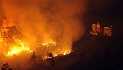 Fire approaches a mansion during a wildfire, Friday, Nov. 14, 2008, in Santa Barbara, Calif. An official in Santa Barbara County, says the fire has destroyed about 70 homes in the upscale community of Montecito. 