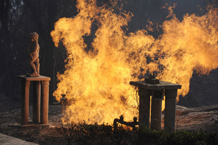 A ruptured gas line burns in front of a large estate as firefighters work to contain a wildfire which has destroyed over 100 homes in the Montecito area of Santa Barbara County, California November 14, 2008.