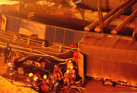Rescuers work at the collapsed road where a subway tunnel was under construction in Hangzhou, capital of east China's Zhejiang Province, Nov. 15, 2008. At least one person is dead and 18 are missing and 13 vehicles were also trapped after the road caved in on a subway tunnel under construction in Hangzhou on November 15, 2008. [Xinhua photo]