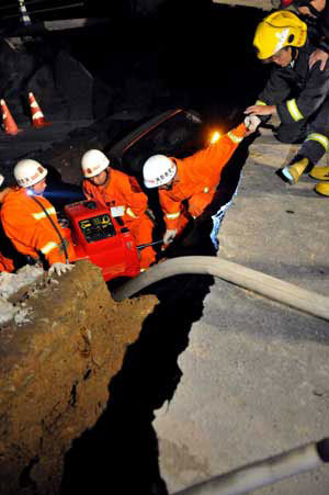 Rescuers work at the collapsed road where a subway tunnel was under construction in Hangzhou, capital of east China's Zhejiang Province, Nov. 15, 2008. At least one person is dead and 18 are missing and 13 vehicles were also trapped after the road caved in on a subway tunnel under construction in Hangzhou on November 15, 2008. [Xinhua photo]