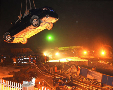 Rescuers work at the collapsed road where a subway tunnel was under construction in Hangzhou, capital of east China's Zhejiang Province, Nov. 15, 2008. At least one person is dead and 18 are missing and 13 vehicles were also trapped after the road caved in on a subway tunnel under construction in Hangzhou on November 15, 2008. [Xinhua photo]