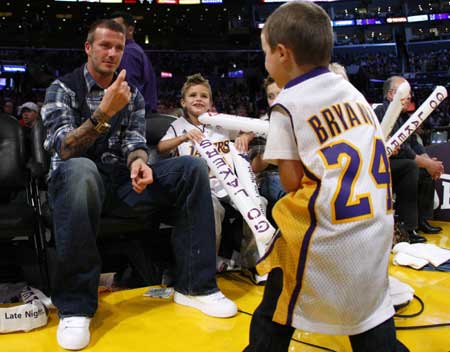 Soccer star David Beckham (L) gestures for his son Cruz (R) to sit down while he sits with his son Romeo, as they watch the Los Angeles Lakers play the Detroit Pistons in their NBA basketball game in Los Angeles November 14, 2008.