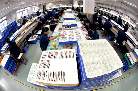 Workers check spectacles on Friday at the Sunhing Glasses Co Ltd in Dongguan, Guangdong province. Authorities in the city recently established two 1-billion-yuan funds to help small and medium enterprises weather the current financial crisis.[Xinhua]