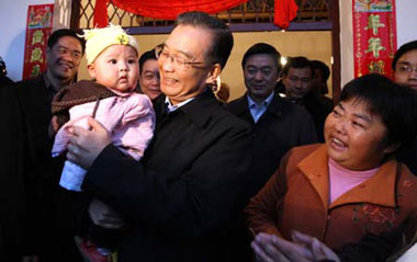 Chinese Premier Wen Jiabao (C) holds a baby while visiting a farmer's newly completed house at Yuejia Village, Mianyang City, Southwest China's Sichuan Province, November 15, 2008.