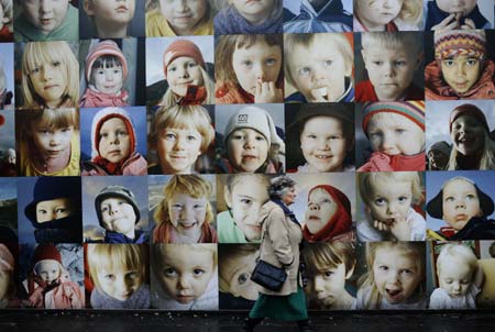 A woman walks past a wall decorated with children's potraits in downtown street of Reykjavik, capital of Iceland, nov. 16, 2008. The Children's Wall consists of some five hundred potrait photos of three to six-year-old children living in the remote area of the country. Several local artists spent about one year to realize the project, which becomes a scenery in the city center of Reykjavik.(Xinhua Photo/Guo Lei) 