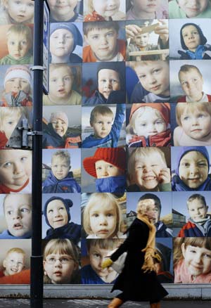 A woman walks past a wall decorated with children's potraits in downtown street of Reykjavik, capital of Iceland, nov. 16, 2008. The Children's Wall consists of some five hundred potrait photos of three to six-year-old children living in the remote area of the country. Several local artists spent about one year to realize the project, which becomes a scenery in the city center of Reykjavik.(Xinhua Photo/Guo Lei)