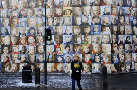 A woman walks past a wall decorated with children's potraits in downtown street of Reykjavik, capital of Iceland, nov. 15, 2008. The Children's Wall consists of some five hundred potrait photos of three to six-year-old children living in the remote area of the country. Several local artists spent about one year to realize the project, which becomes a scenery in the city center of Reykjavik.(Xinhua Photo/Guo Lei)