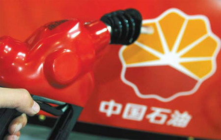 A file photo shows an attendant holds a petrol pump at a CNPC gas station in Beijing. [China Daily]