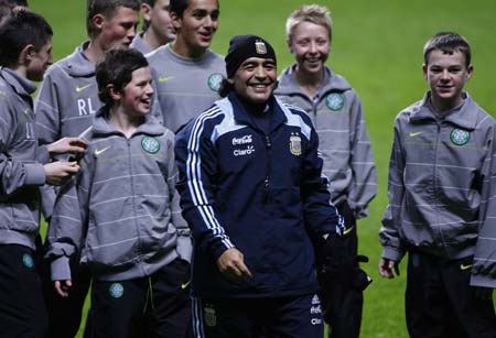 Argentina's soccer team head coach Diego Maradona laughs with Celtic Park stadium ball boys after they helped find a necklace Maradona lost during a training session at Celtic Park stadium in Glasgow, Scotland November 17, 2008. Argentina play Scotland in an international friendly soccer match at Hampden Park stadium on Wednesday.[Agencies] 