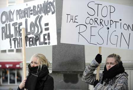 Two protestors hold posters during a rally in Reykjavik, capital of Iceland, Nov. 15, 2008. Thousands of demonstrators took part in a rally here, calling on the government to resign for the national financial crisis. Iceland's central bank has raised its benchmark interest rate to 18% after the government took control of the three largest banks, however, the Icelandic economy remain in unprecedented turbulence, due to the lack of international aid loans and public confidence, and trade shrinking.