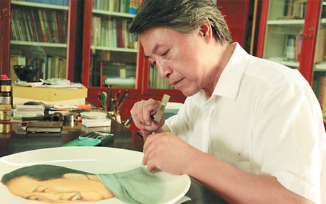 Li Ziyuan carves on a ceramic plate an image of late Chairman Mao Zedong at his studio in Zibo, Shandong province. 