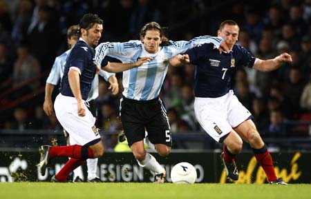 Argentina's Fernando Gago (C) barges through Scotland's Paul Hartley (L) and Scott Brown during their international friendly soccer match at Hampden Park stadium in Glasgow, Scotland November 19, 2008. [Xinhua/Reuters]