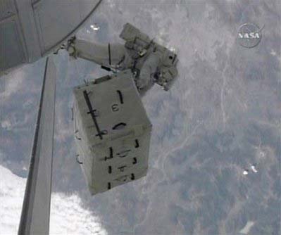 In this image from NASA TV, astronaut Heidemarie Stefanyshyn-Piper, attached to the end of a robotic arm, maneuvers an empty nitrogen tank toward the cargo bay of the docked space shuttle Endeavour, Tuesday, November 18, 2008. 