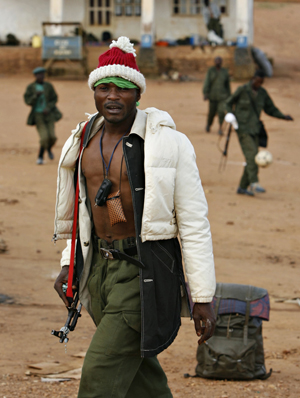 A government soldier walks through the looted village of Kayna after a day of fighting in eastern Congo, November 18, 2008. Rebels in east Democratic Republic of Congo announced a military pullback on Tuesday to support a U.N. peace initiative and the government sacked its armed forces chief following a string of defeats.