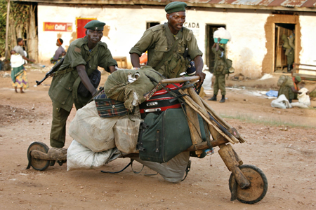 Government soldiers transport looted goods on a wooden bicycle after a day of fighting in the village of Kayna in eastern Congo, November 18, 2008. Demoralised Congolese government troops, retreating before eastern rebels, clashed on Tuesday with their own local militia allies who tried to make them stand and fight after the armed forces chief was replaced. 