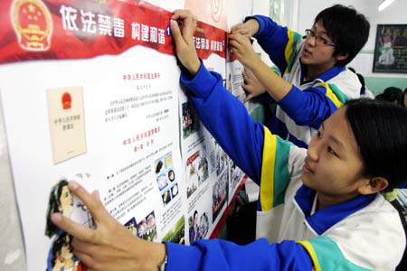 Students stick on the placard on National Narcotics Ban Awareness for All the Public, in the classroom of Yuhong Middle School, in north China's Tianjin Municipality, Nov. 19, 2008. Policemen on duty get on the campus to promote the knowledges and discretion of students on their understanding of the drugs ban, discerning the narcotics ban, and self-protection from drugs as well. 