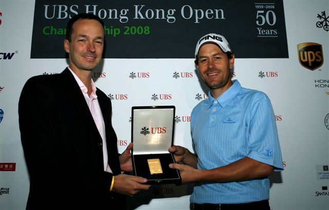 In reward for his hole-in-one, England's Simon Griffiths is delighted to accept a gold brick from Oliver Bertschinger, Head of Sponsorship of UBS Asia Pacific.