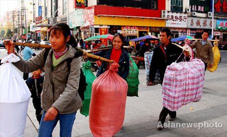 Migrant workers carrying their belongings walk out of the Nanchang railway station in Jiangxi province November 20, 2008. Hundreds of thousands of workers have returned home from cities, becoming the worst victims of the global financial crisis. [China Daily]